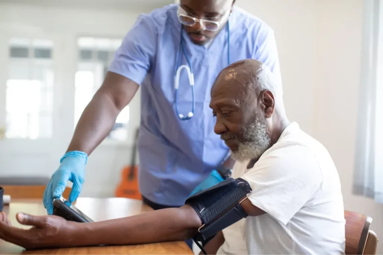 Nurse checking elderly man's blood pressure.
