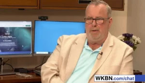 Man in beige blazer discussing website content.